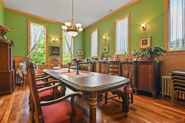 dining space featuring crown molding, hardwood / wood-style floors, and a chandelier