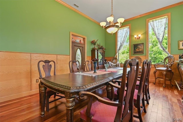 dining space with ornamental molding, hardwood / wood-style floors, and an inviting chandelier