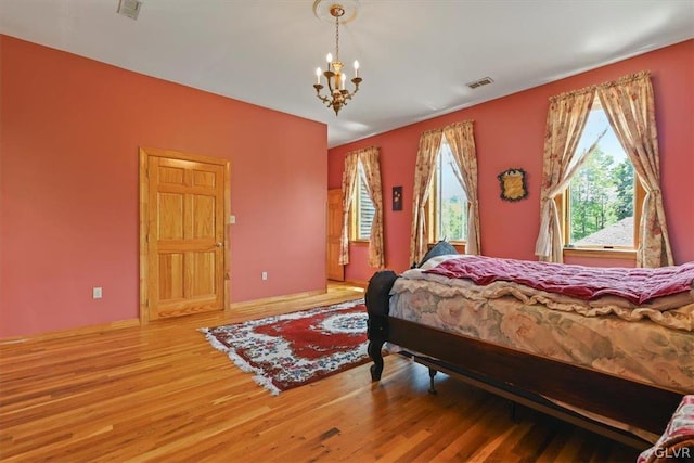 bedroom with an inviting chandelier and hardwood / wood-style flooring