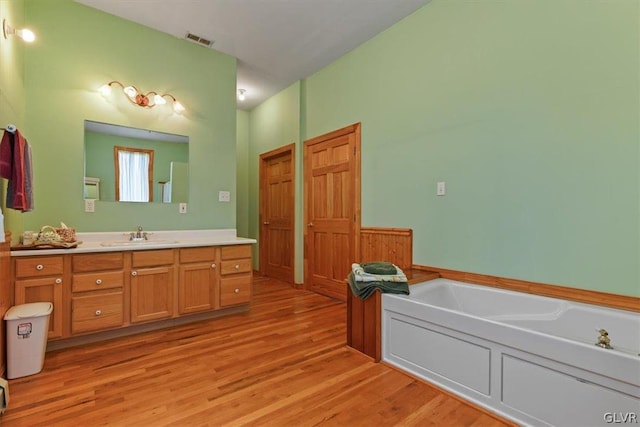 bathroom with vanity, a bathing tub, and hardwood / wood-style flooring