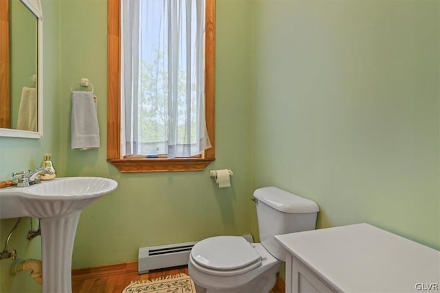 bathroom with wood-type flooring, a baseboard heating unit, and toilet