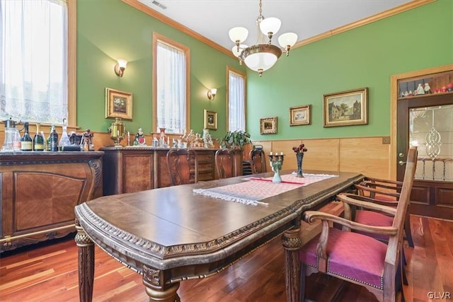 dining space with hardwood / wood-style flooring, a notable chandelier, and crown molding