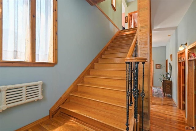 stairs featuring hardwood / wood-style floors and radiator heating unit