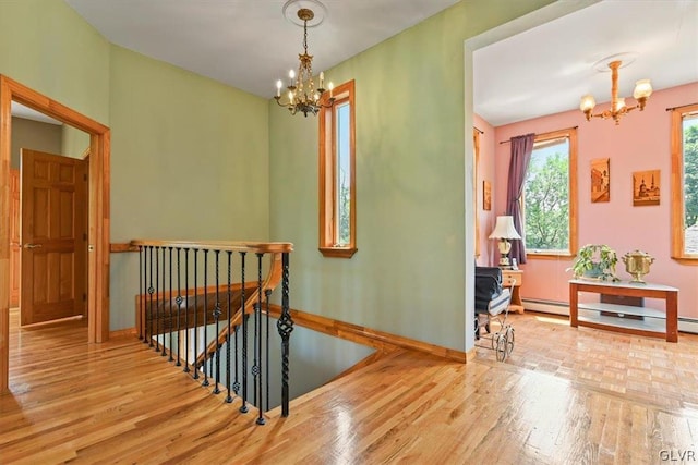 hall with a baseboard radiator, wood-type flooring, and a notable chandelier