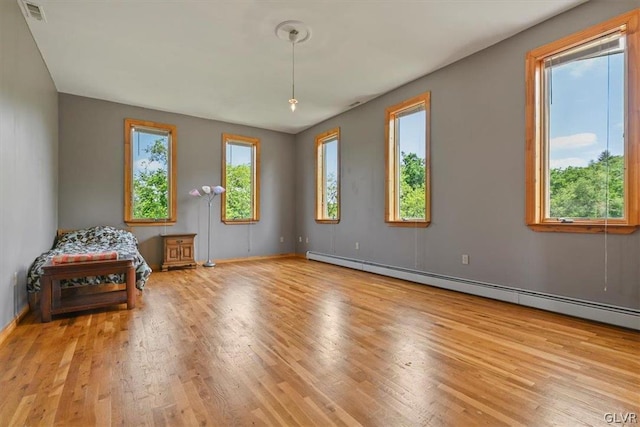 interior space featuring light hardwood / wood-style floors, baseboard heating, and a wealth of natural light