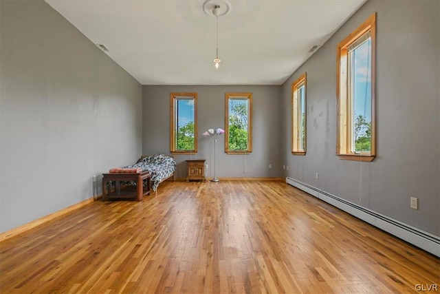 empty room featuring a baseboard radiator and light hardwood / wood-style floors