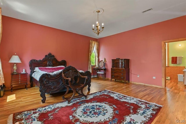 bedroom featuring a baseboard heating unit, an inviting chandelier, and hardwood / wood-style flooring