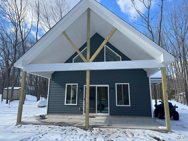 snow covered rear of property with an outdoor structure