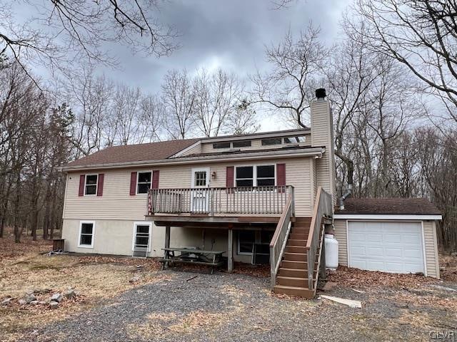 rear view of property with a wooden deck and a garage