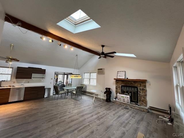 living room with dark hardwood / wood-style floors, a stone fireplace, an AC wall unit, ceiling fan, and lofted ceiling with skylight