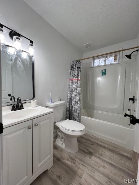 full bathroom featuring a textured ceiling, shower / bath combo with shower curtain, hardwood / wood-style flooring, toilet, and vanity