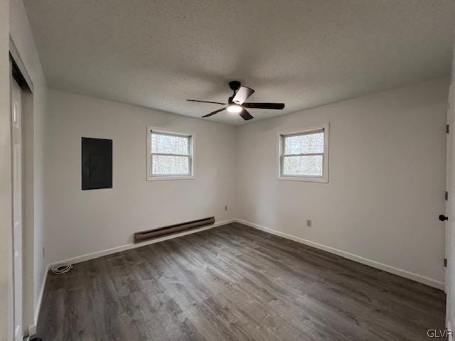 spare room featuring dark hardwood / wood-style floors, a baseboard heating unit, and a healthy amount of sunlight