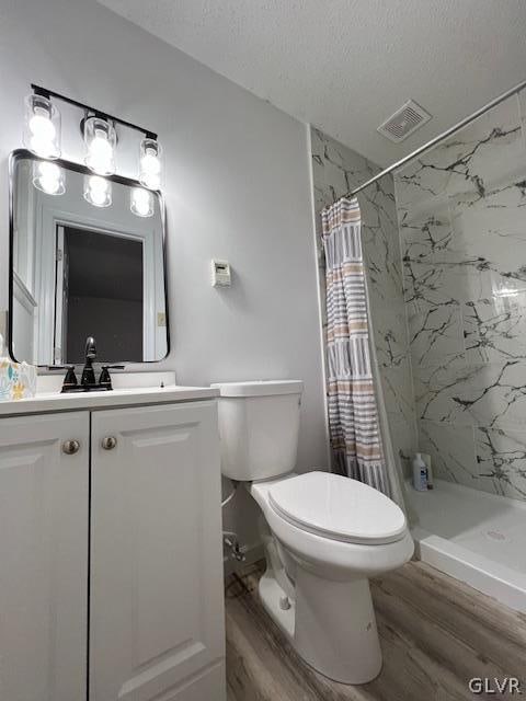 bathroom with wood-type flooring, a textured ceiling, toilet, and a shower with curtain