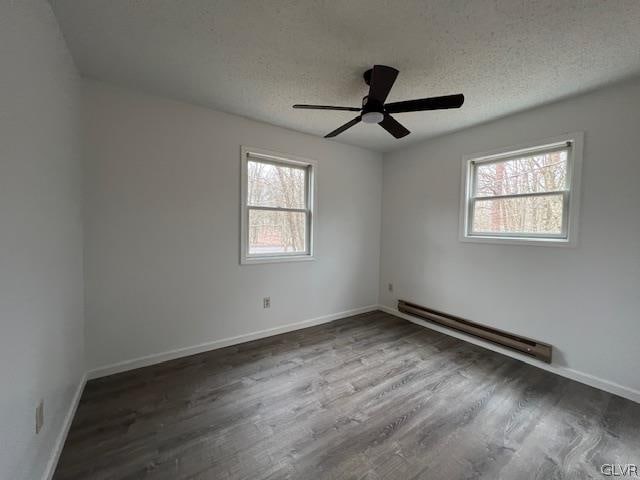 spare room featuring ceiling fan, a baseboard heating unit, hardwood / wood-style flooring, and a textured ceiling