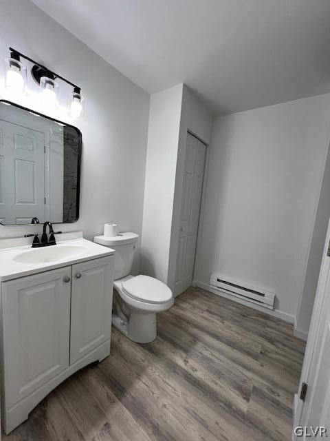 bathroom featuring toilet, vanity, wood-type flooring, and baseboard heating