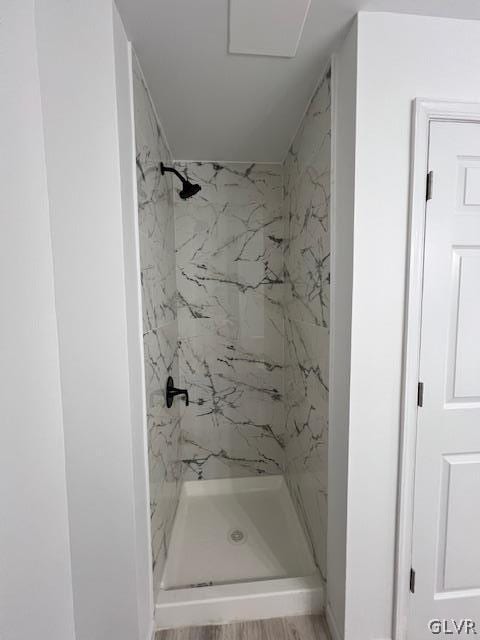 bathroom with a tile shower and hardwood / wood-style flooring