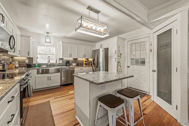 kitchen featuring appliances with stainless steel finishes, light hardwood / wood-style flooring, and light stone countertops