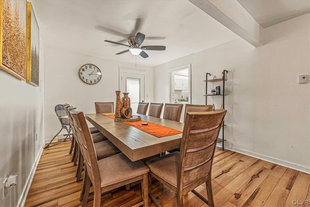 dining area featuring beamed ceiling, ceiling fan, and light wood-type flooring