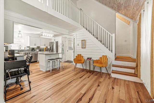 living room featuring wooden ceiling, sink, light wood-type flooring, and high vaulted ceiling