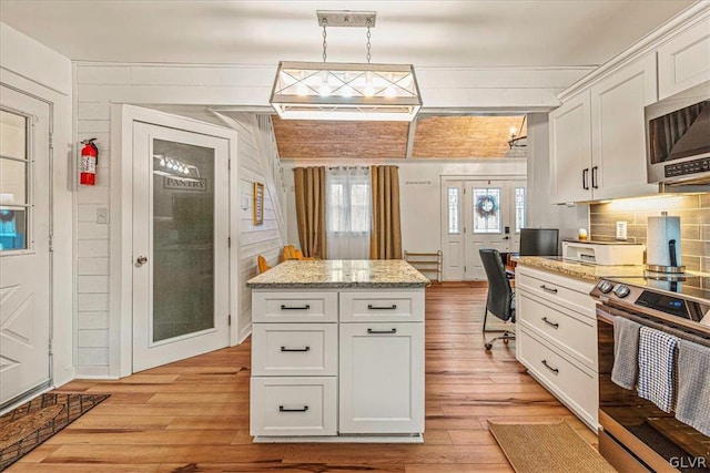 kitchen featuring appliances with stainless steel finishes, white cabinetry, decorative light fixtures, and light wood-type flooring