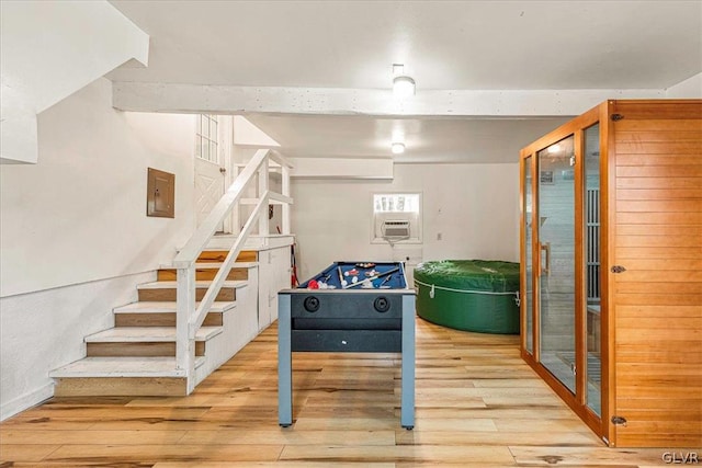 recreation room featuring a wall mounted AC and light hardwood / wood-style floors