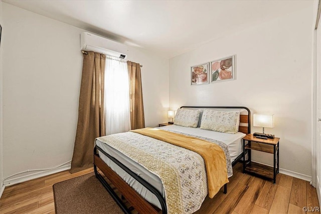 bedroom with a wall unit AC and hardwood / wood-style floors