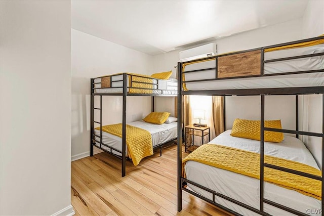 bedroom featuring light hardwood / wood-style flooring and a wall mounted air conditioner