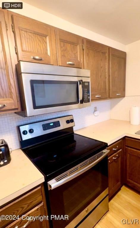 kitchen featuring appliances with stainless steel finishes, tasteful backsplash, and light hardwood / wood-style floors