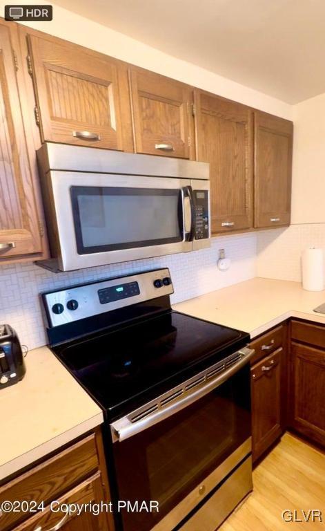 kitchen with light hardwood / wood-style floors, appliances with stainless steel finishes, and decorative backsplash