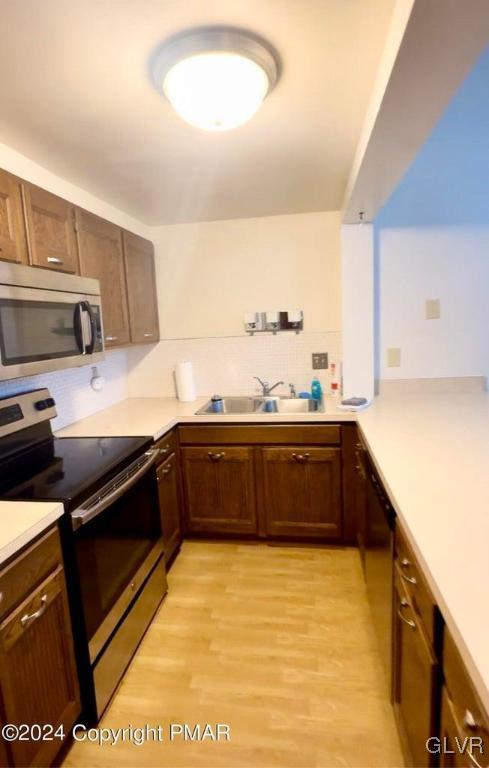 kitchen featuring sink, backsplash, stainless steel appliances, and light hardwood / wood-style floors