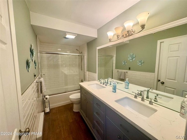 full bathroom with enclosed tub / shower combo, double sink vanity, toilet, and hardwood / wood-style floors