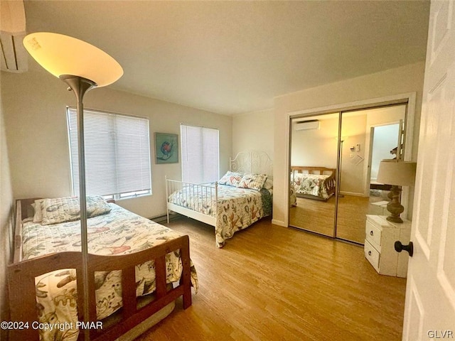 bedroom featuring an AC wall unit, light hardwood / wood-style flooring, and a closet