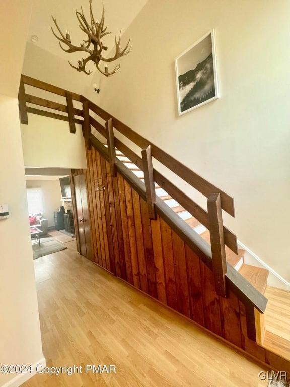 stairway with hardwood / wood-style floors and an inviting chandelier