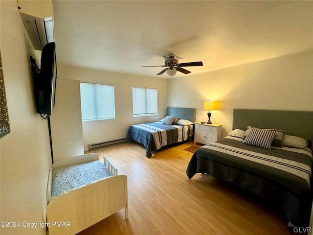 bedroom featuring ceiling fan, a baseboard heating unit, and light hardwood / wood-style floors