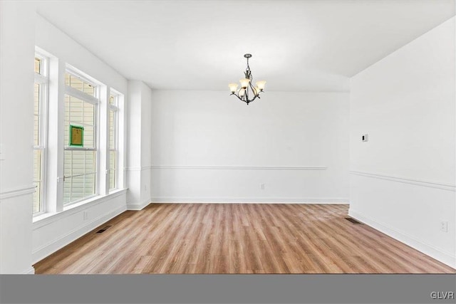 unfurnished room with light hardwood / wood-style flooring and a notable chandelier