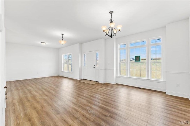 unfurnished living room with a chandelier and light wood-type flooring