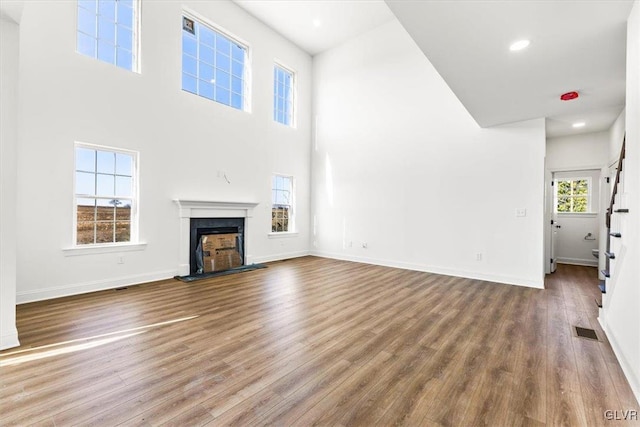 unfurnished living room with a high ceiling and wood-type flooring