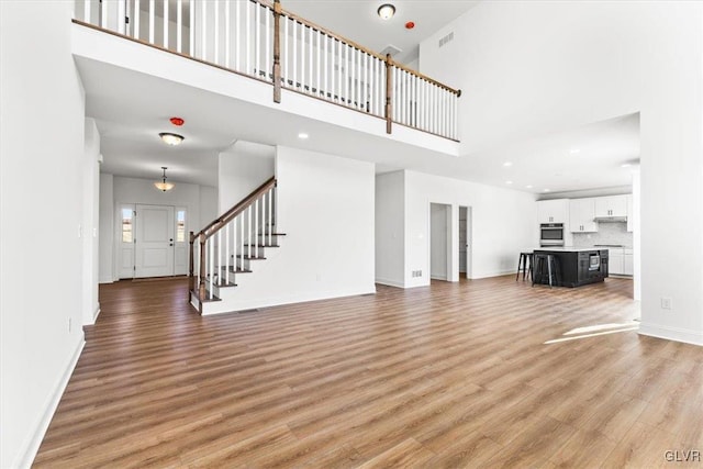 unfurnished living room featuring a high ceiling and light wood-type flooring