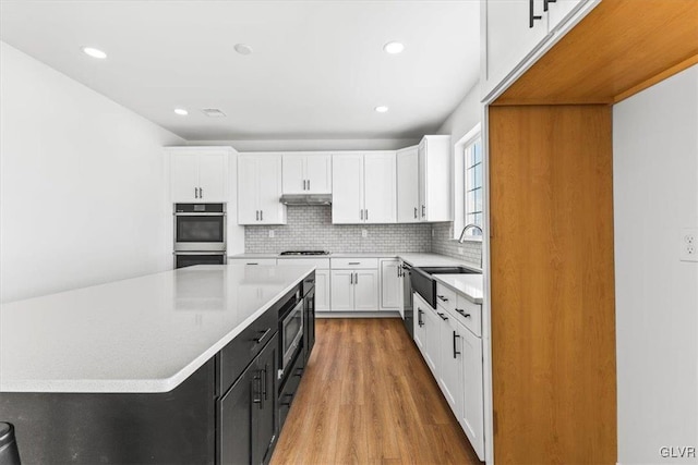 kitchen featuring a kitchen island, white cabinetry, appliances with stainless steel finishes, sink, and light hardwood / wood-style floors