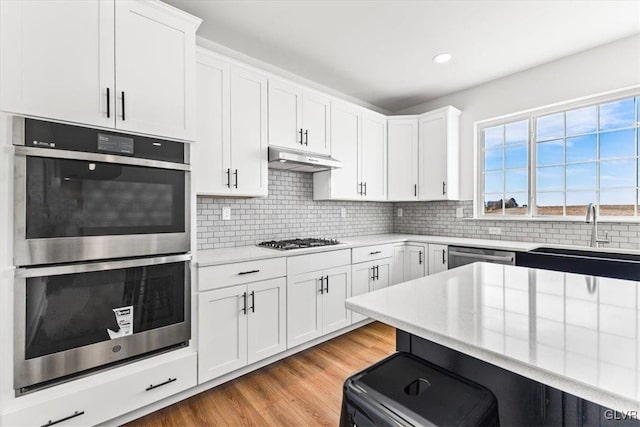 kitchen with white cabinets, light hardwood / wood-style floors, stainless steel appliances, and sink