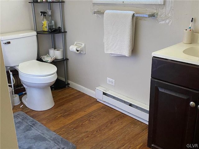 bathroom featuring wood-type flooring, baseboard heating, vanity, and toilet