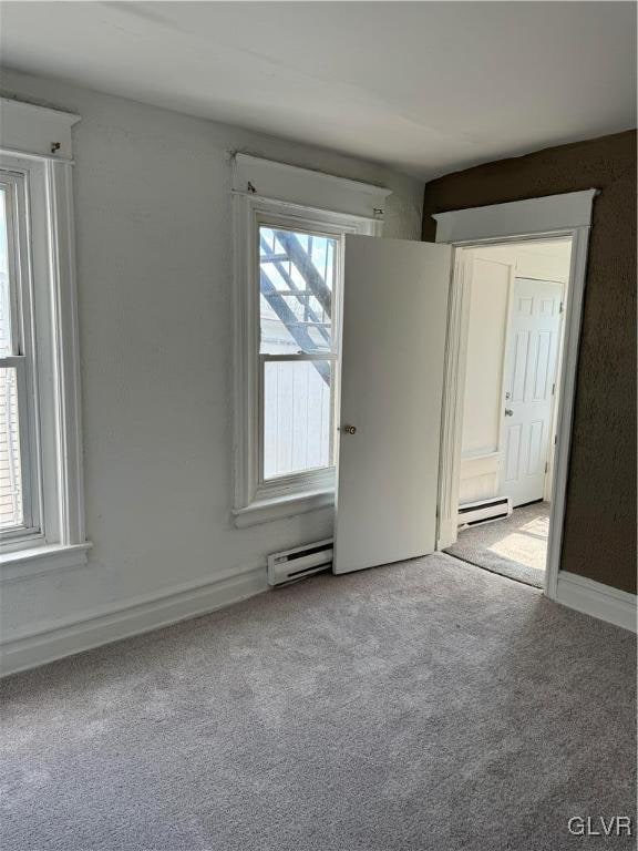 carpeted spare room featuring a baseboard radiator