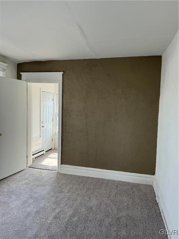 carpeted spare room with a baseboard radiator