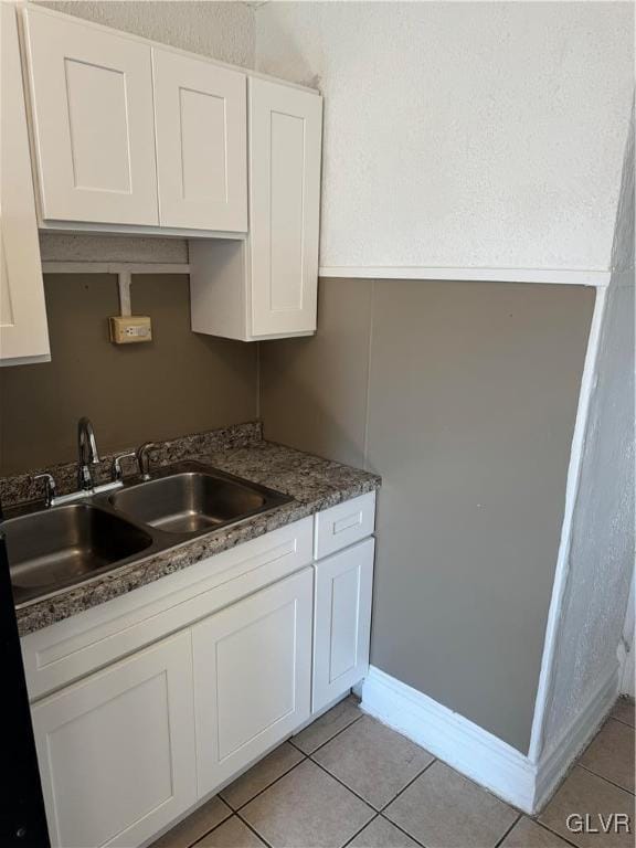 kitchen featuring white cabinets, light tile patterned flooring, and sink