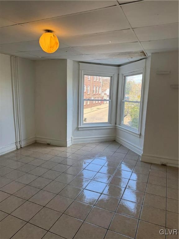 tiled spare room with a drop ceiling