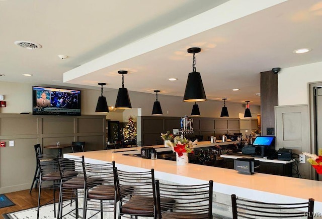 interior space with light hardwood / wood-style floors, decorative light fixtures, and a breakfast bar