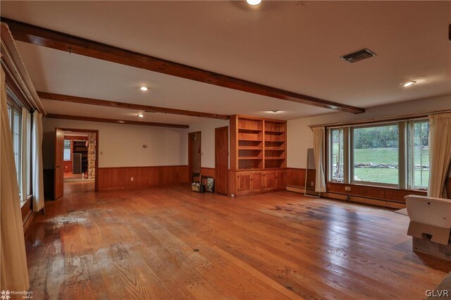 unfurnished living room featuring hardwood / wood-style floors and beam ceiling