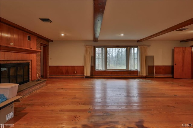 unfurnished living room with a baseboard heating unit, hardwood / wood-style floors, and beamed ceiling