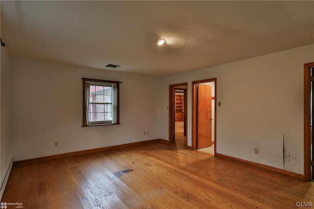 empty room with a baseboard radiator and light hardwood / wood-style floors