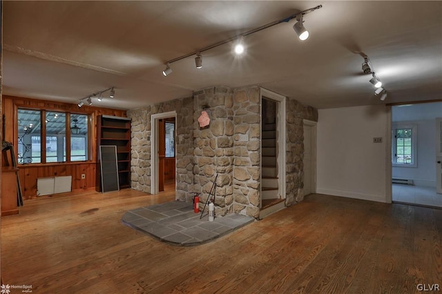 basement featuring a baseboard heating unit, wood-type flooring, and radiator heating unit